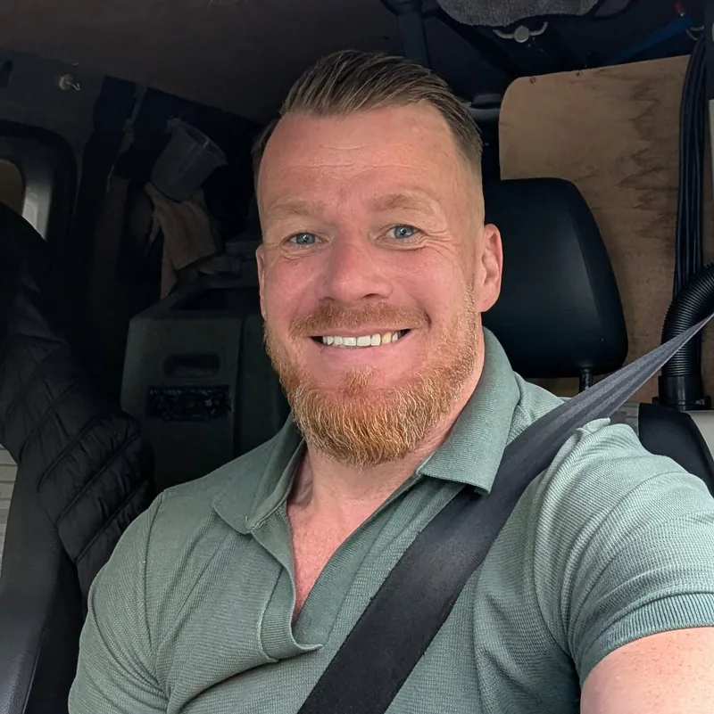 Ed, owner of Ed's Carpet Cleaning, smiling in his van